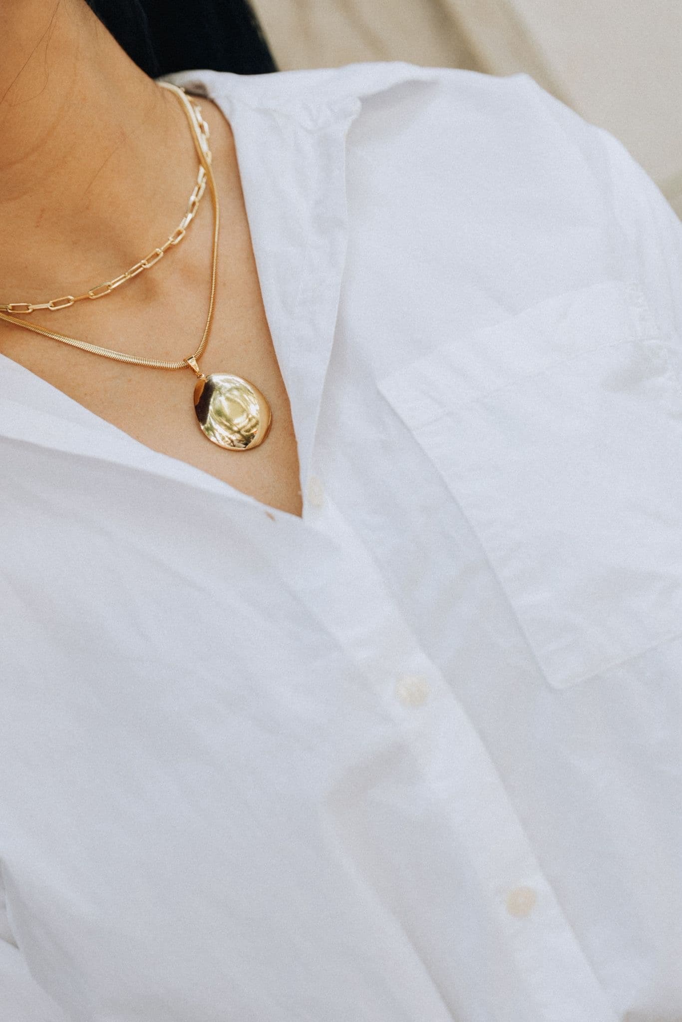 Colar com pingente dourado em camisa branca