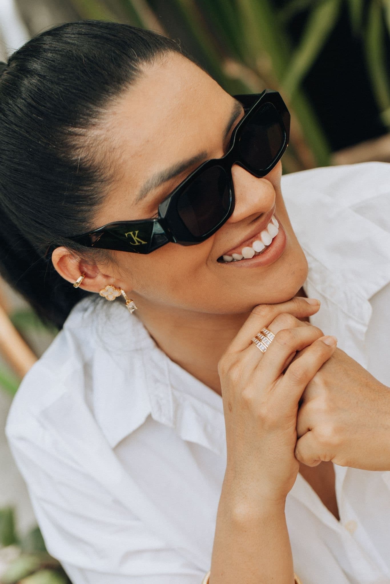 Modelo sorrindo com brincos e aneis dourados